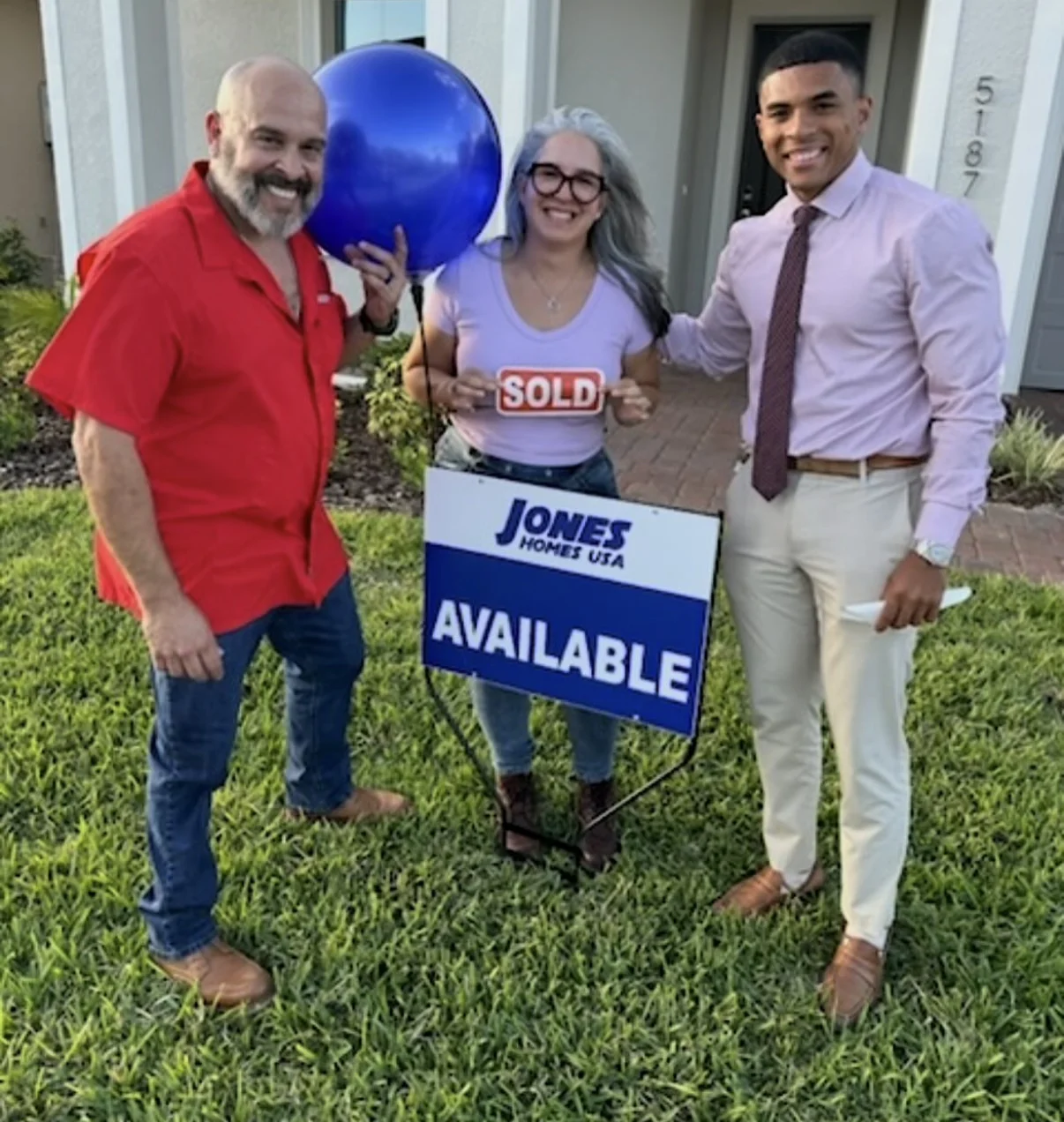 Brandon Cruz with two people outside a home, beside a Jones Homes sign